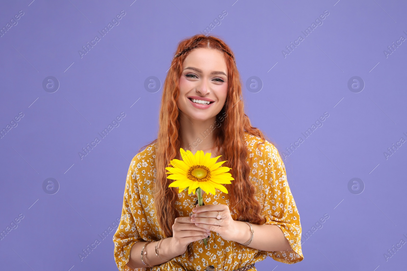 Photo of Beautiful young hippie woman with sunflower on violet background
