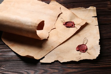Photo of Sheets of old parchment paper with wax stamps on wooden table