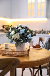Photo of Beautiful winter bouquet on wooden table in kitchen