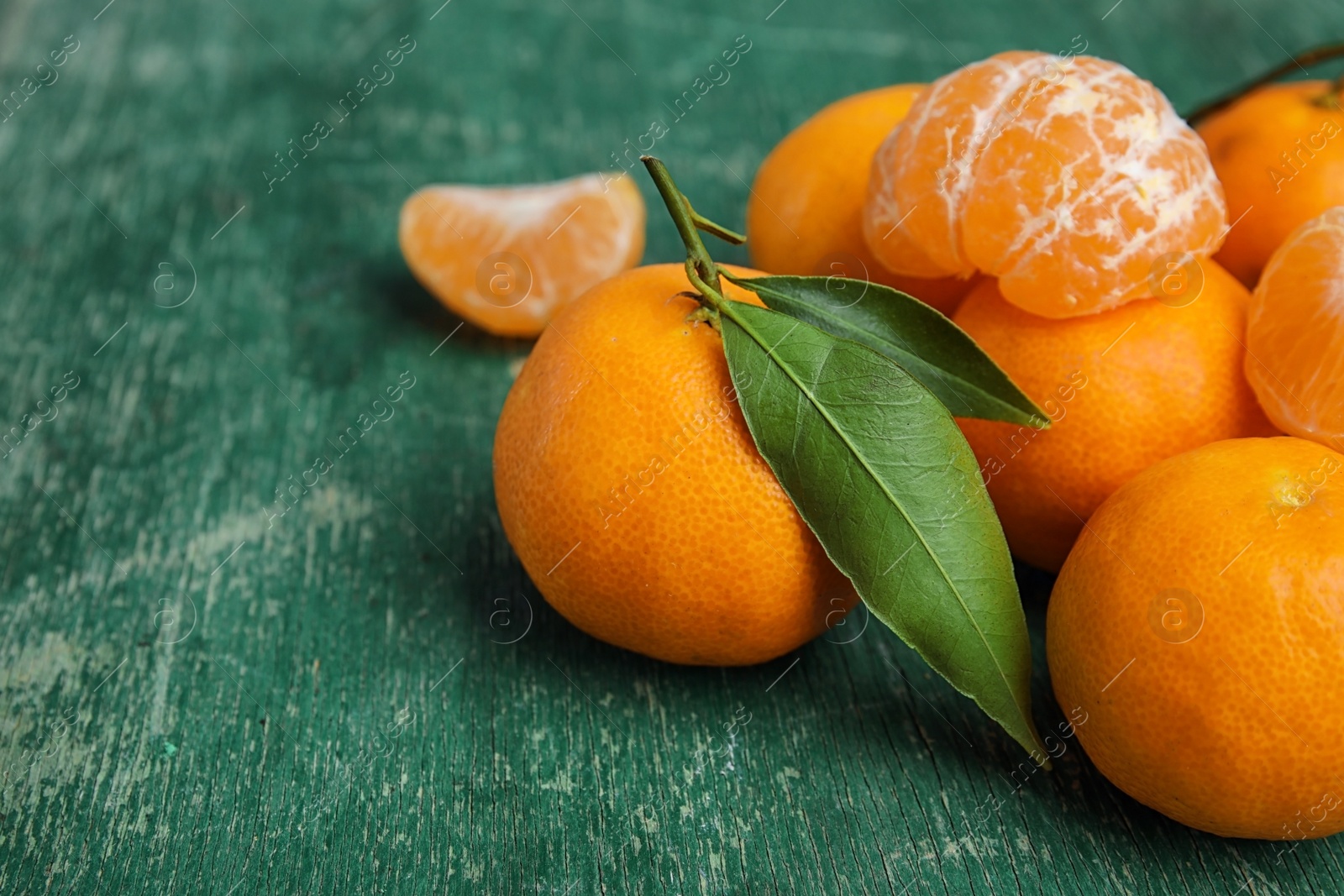 Photo of Fresh ripe tangerines with green leaves on table