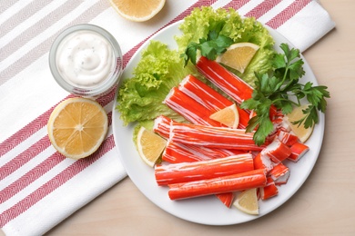 Delicious crab sticks served on wooden table, flat lay