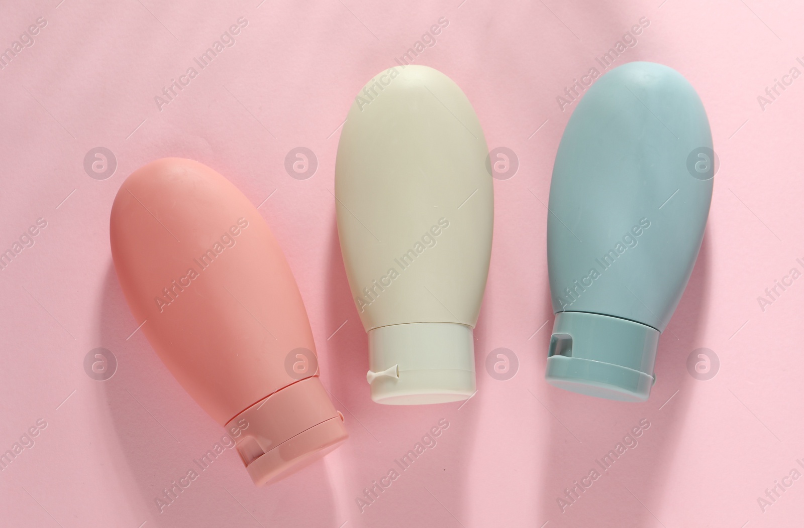 Photo of Cosmetic travel kit on pink background, top view