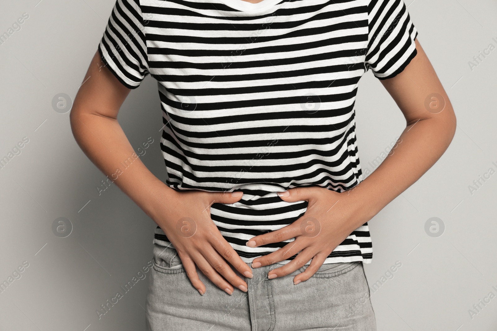 Photo of Young woman suffering from menstrual pain on grey background, closeup