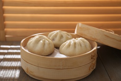 Photo of Delicious bao buns (baozi) on wooden table, closeup