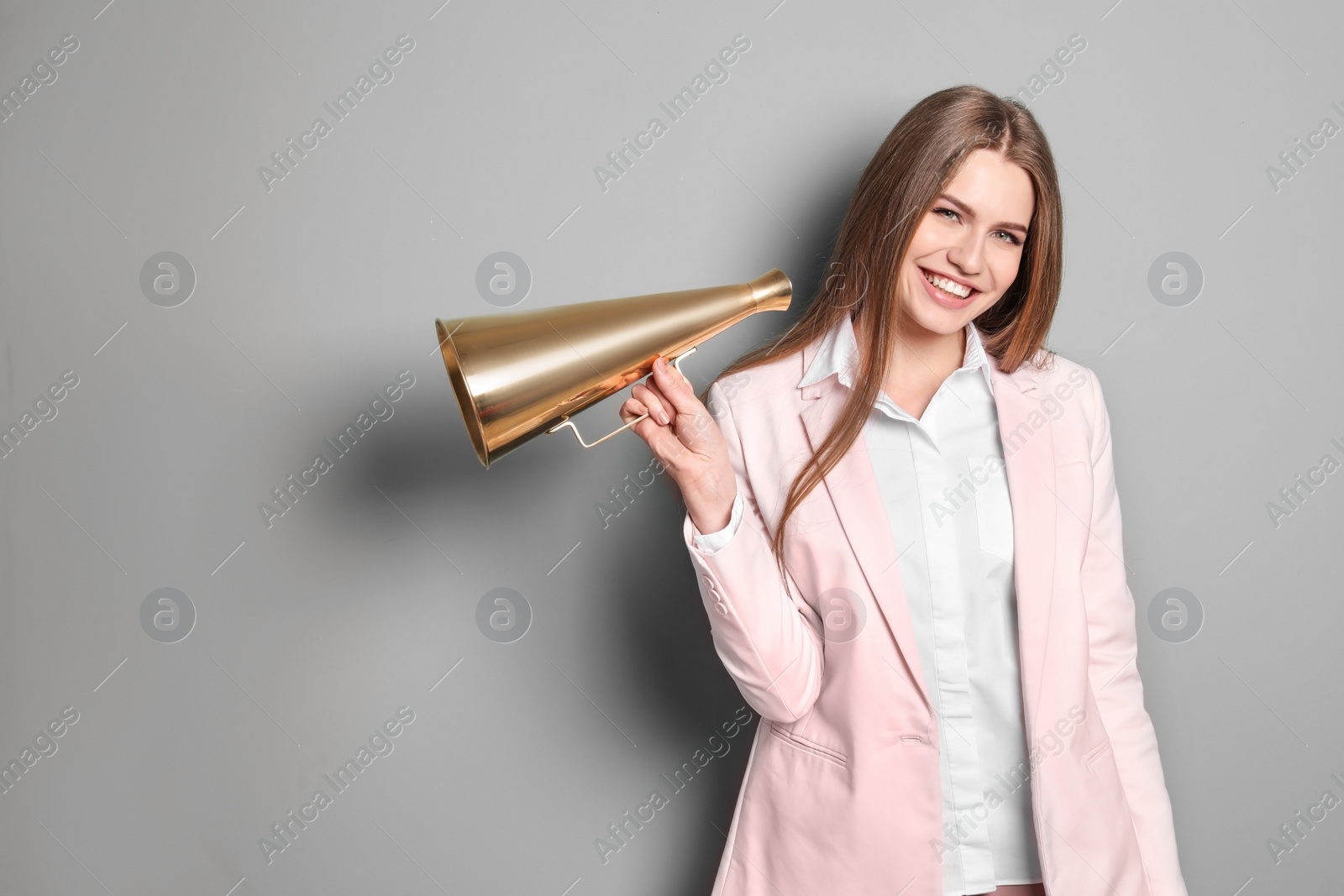 Photo of Young woman with megaphone on grey background