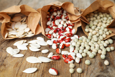 Photo of Different vegetable seeds on wooden table, closeup