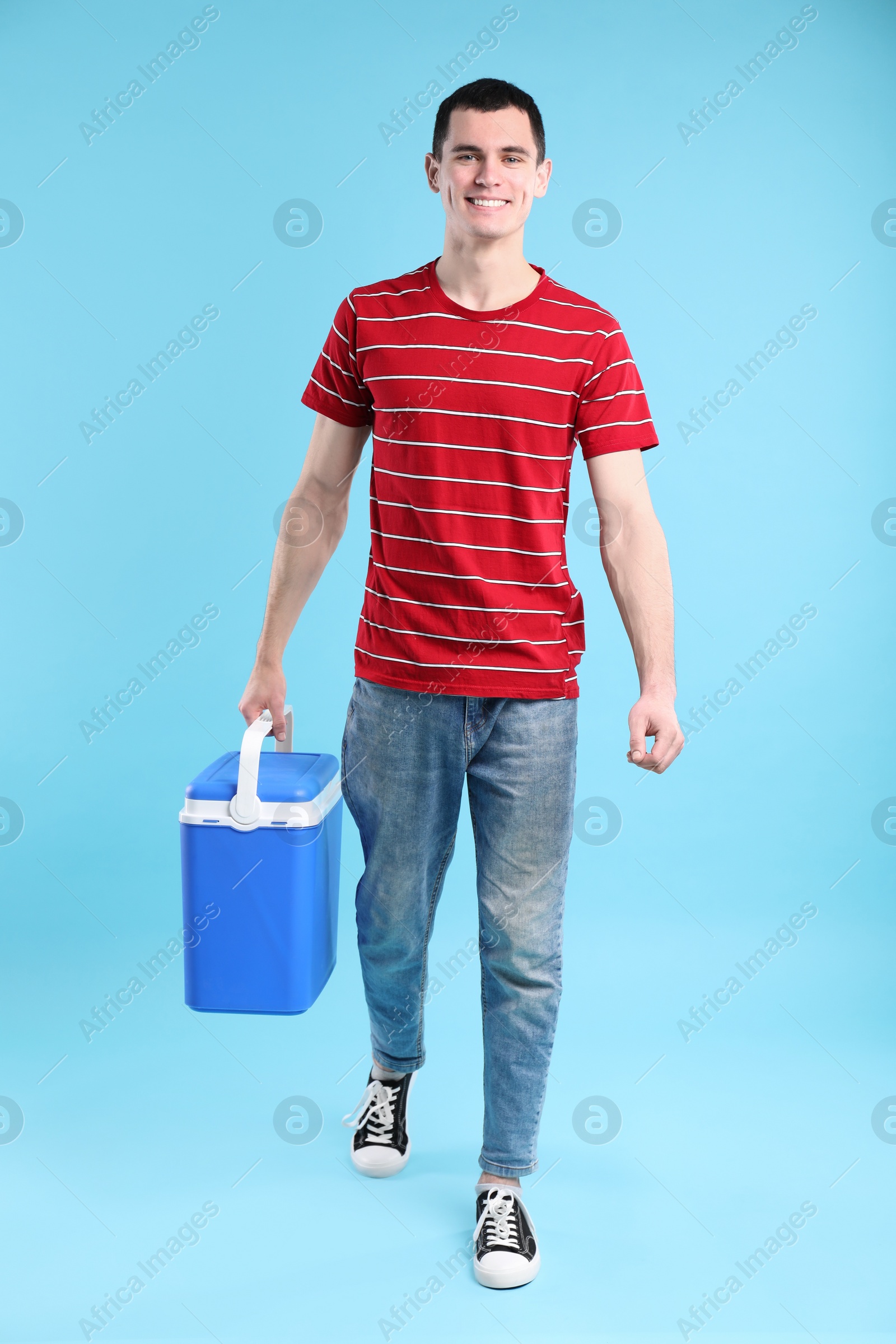 Photo of Man with cool box walking on light blue background