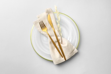 Photo of Stylish setting with cutlery, napkin, dry branch and plate on light grey table, top view