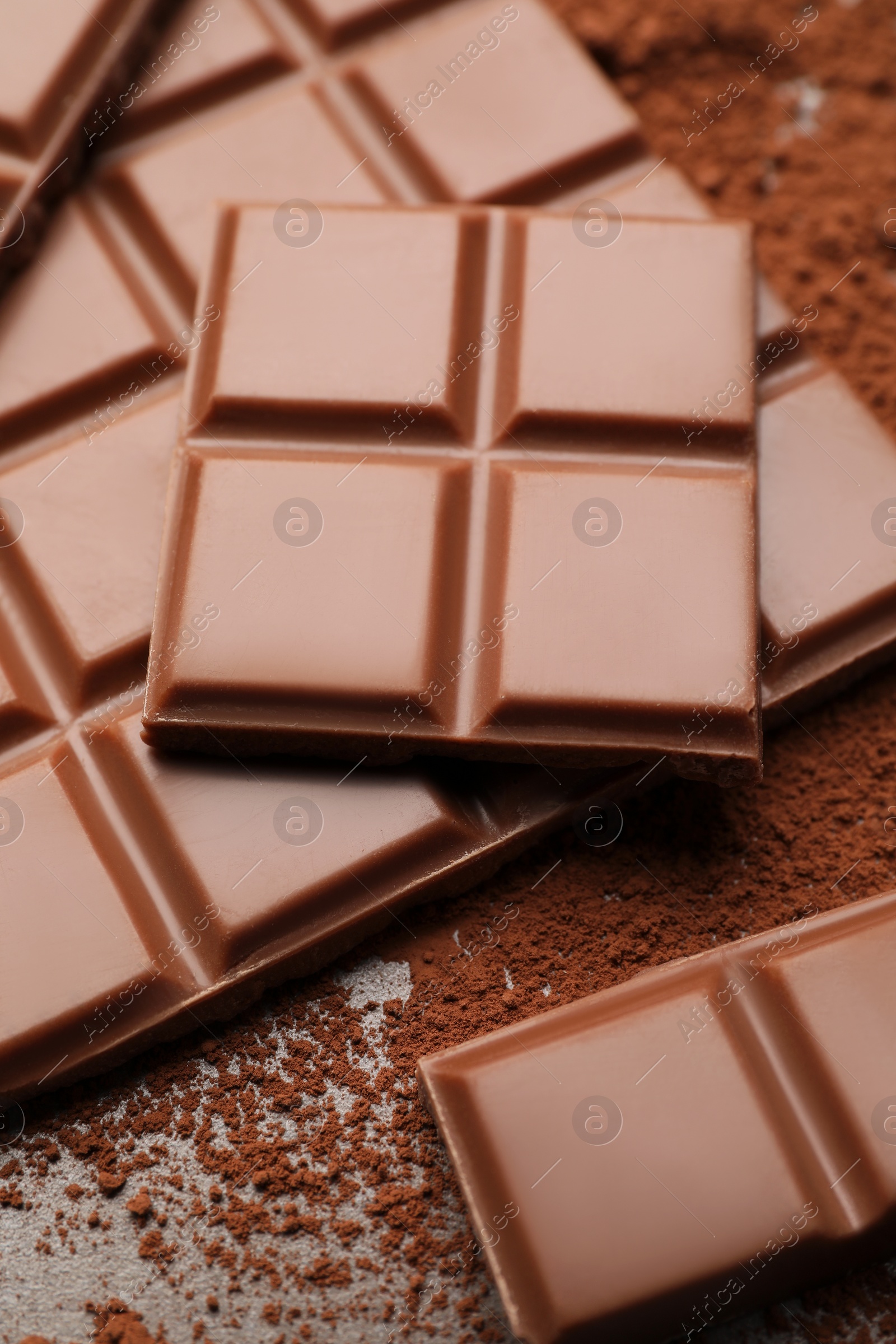 Photo of Delicious milk chocolate and cocoa powder on table, closeup