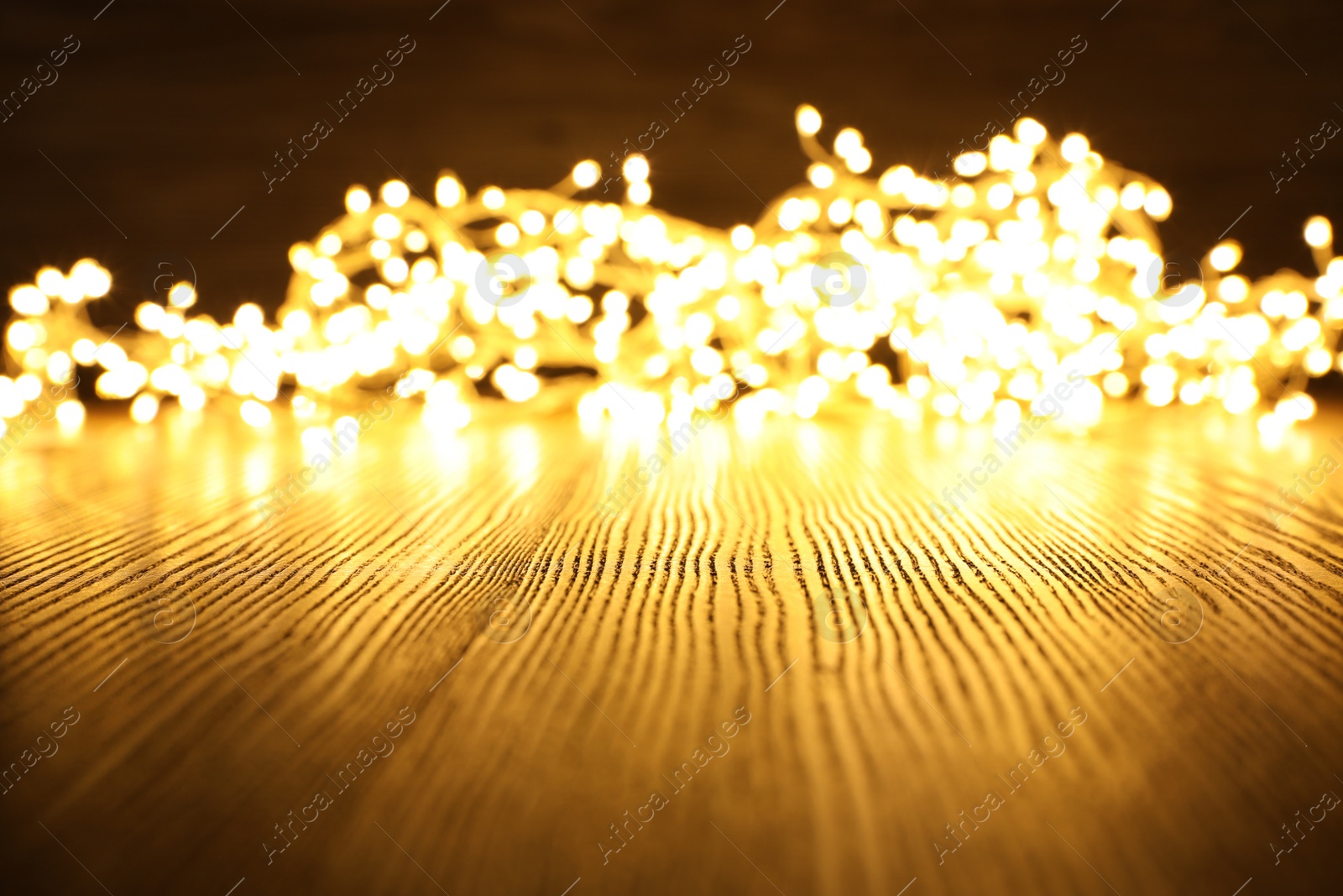 Photo of Beautiful glowing Christmas lights on wooden table. Space for text