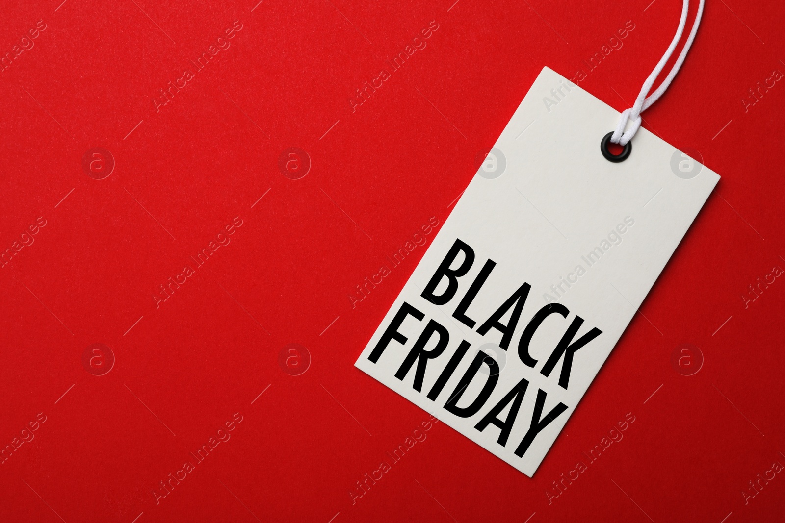 Image of White tag with phrase BLACK FRIDAY on red background, top view. Space for text