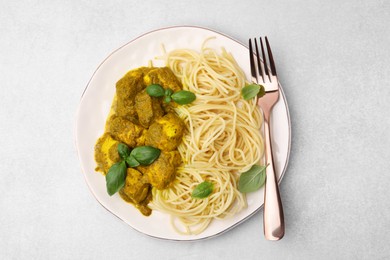 Photo of Delicious chicken, pasta with curry sauce and basil served on white table, top view