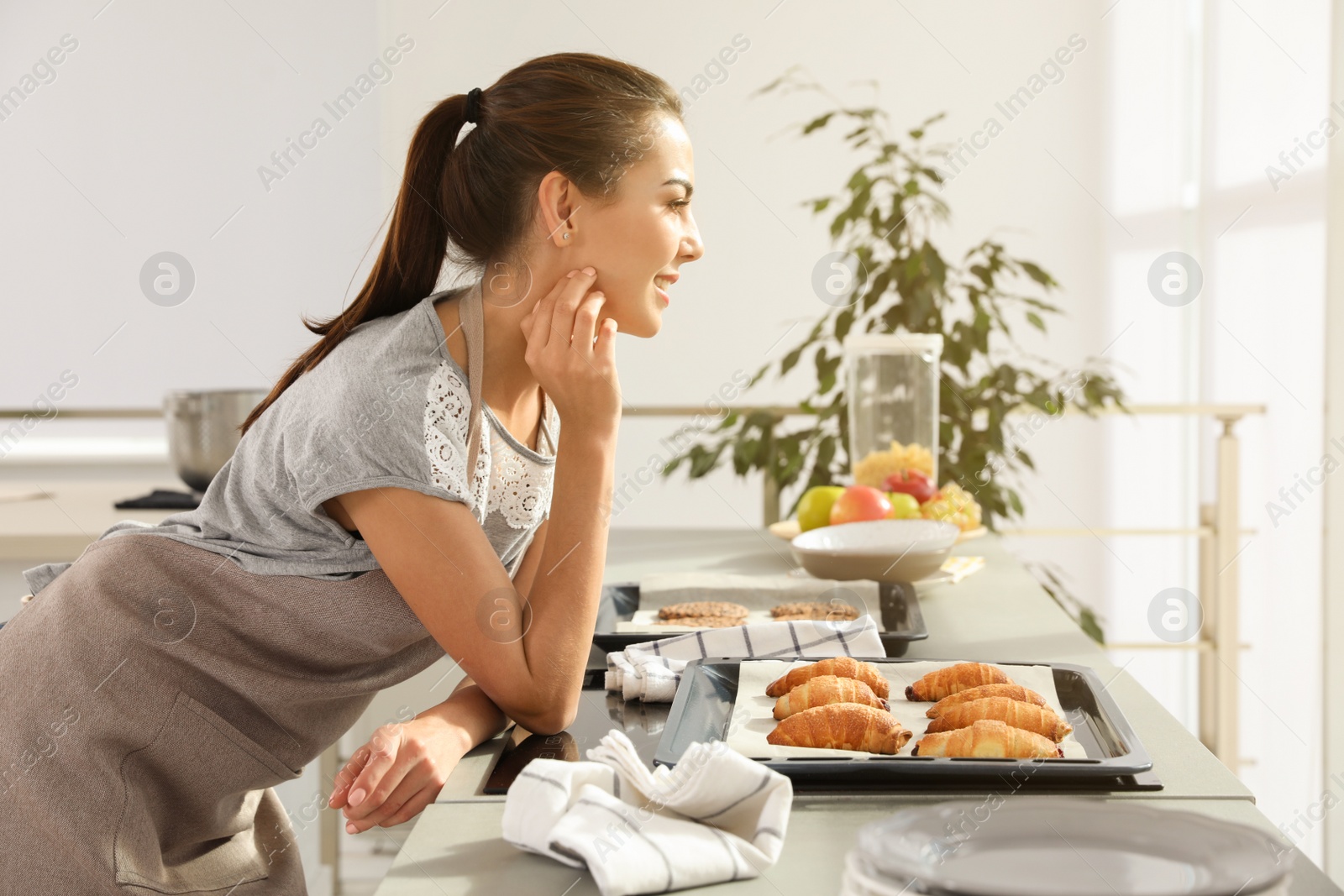 Photo of Young woman with homemade oven baked pastry  in kitchen