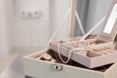 Jewelry box with mirror and many accessories on table indoors, closeup