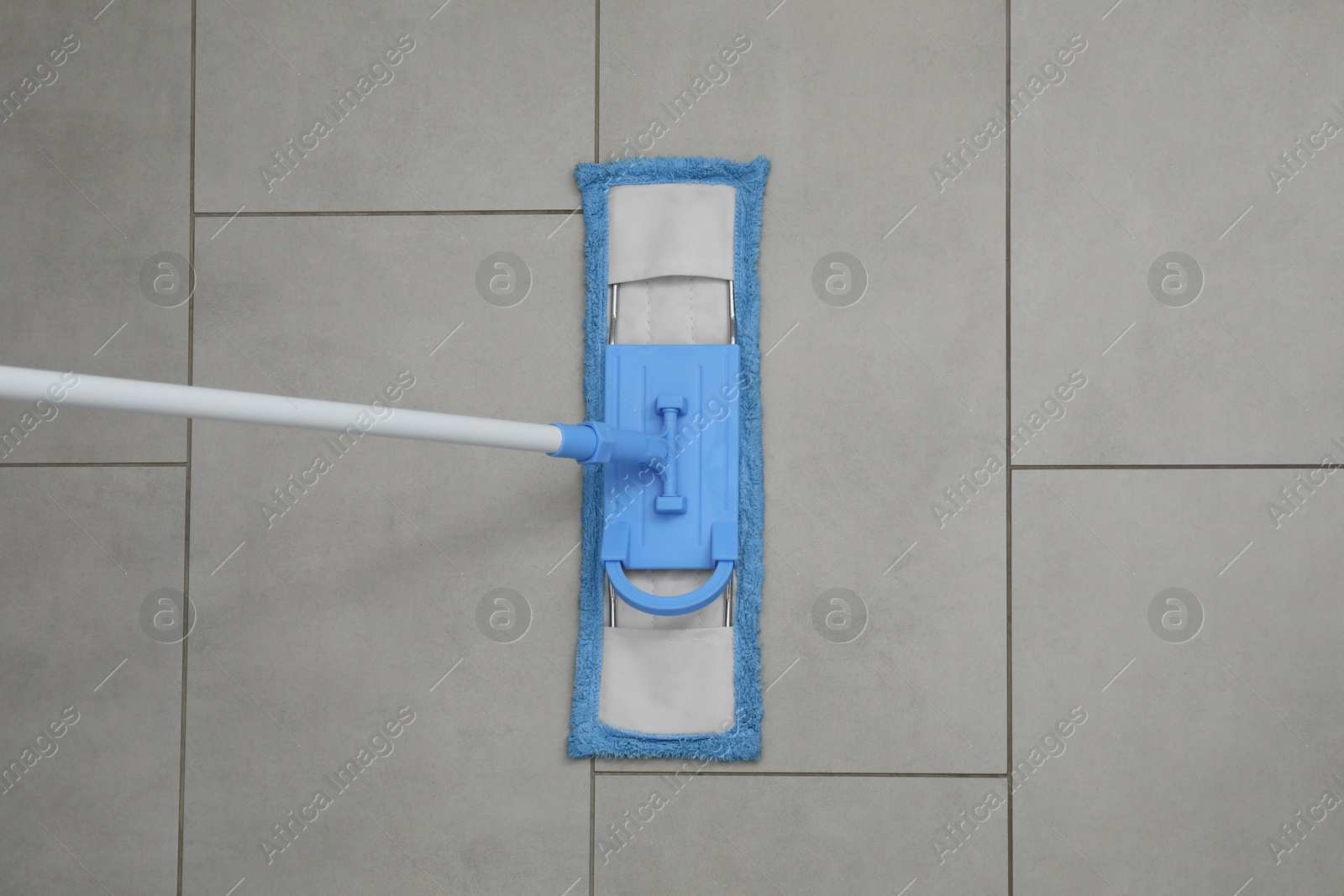 Photo of Cleaning grey tiled floor with mop, top view