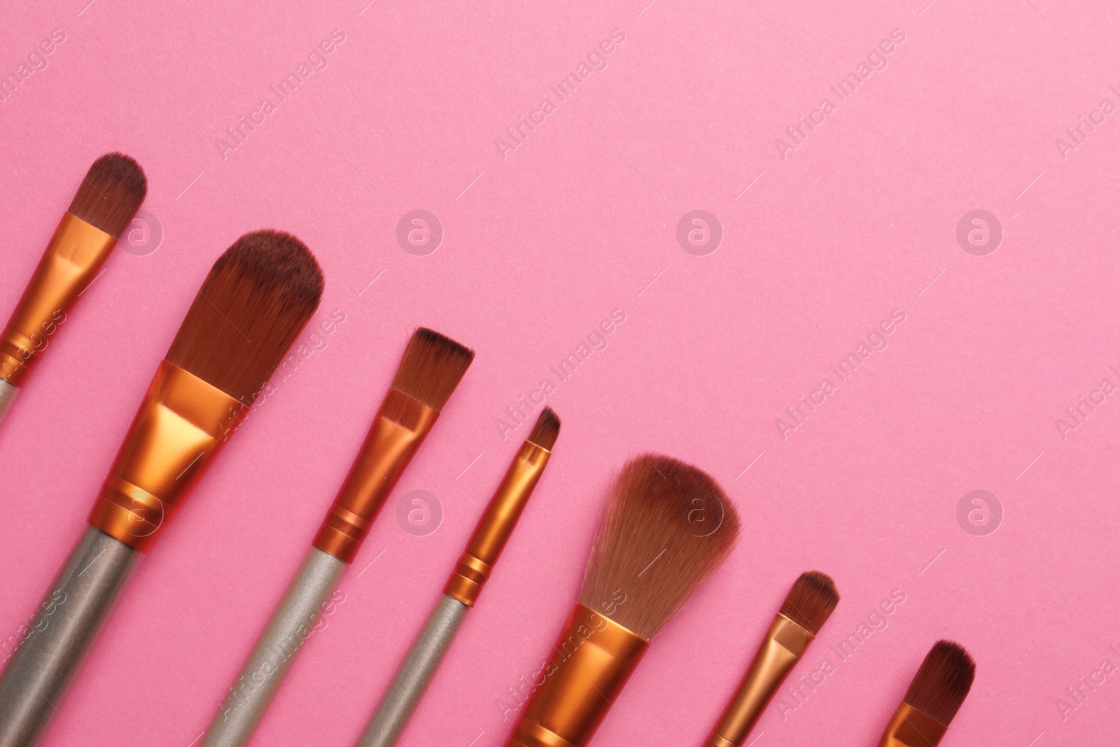 Photo of Set of makeup brushes on pink background, flat lay. Space for text