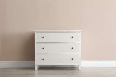 Photo of White chest of drawers near beige wall