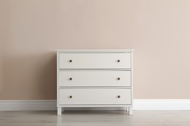 White chest of drawers near beige wall