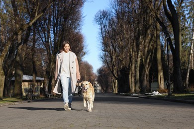 Photo of Young woman walking with adorable Labrador Retriever on sunny day outdoors. Space for text