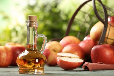 Photo of Composition with jug of apple vinegar on table. Space for text