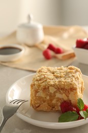 Photo of Piece of delicious Napoleon cake, raspberries and fork on beige table