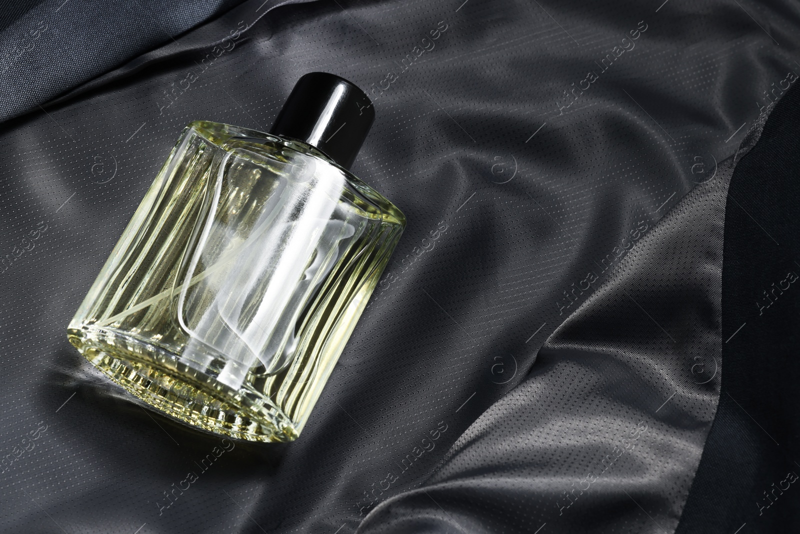 Photo of Luxury men's perfume in bottle on grey jacket, space for text