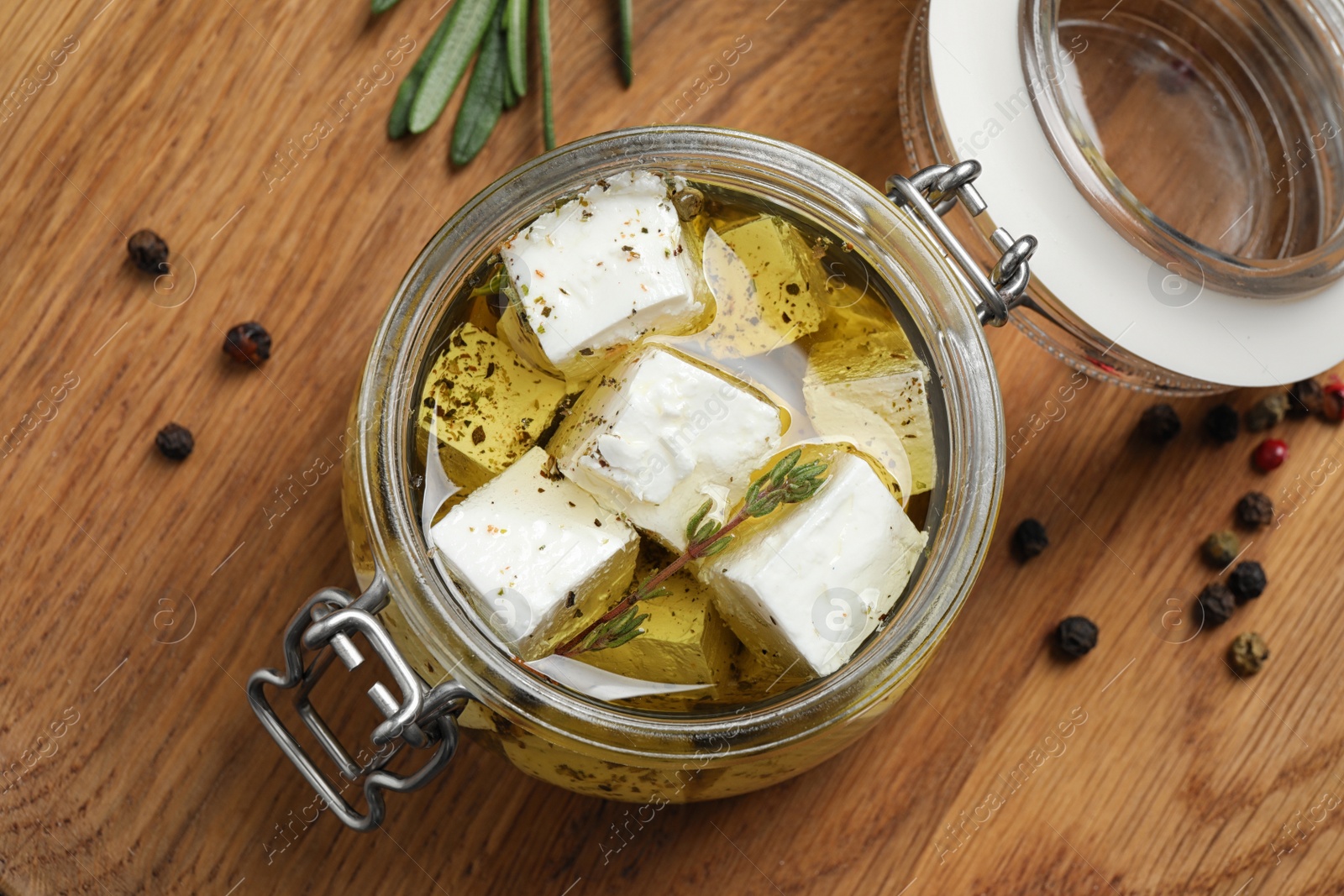 Photo of Jar with feta cheese marinated in oil on wooden table, flat lay. Pickled food