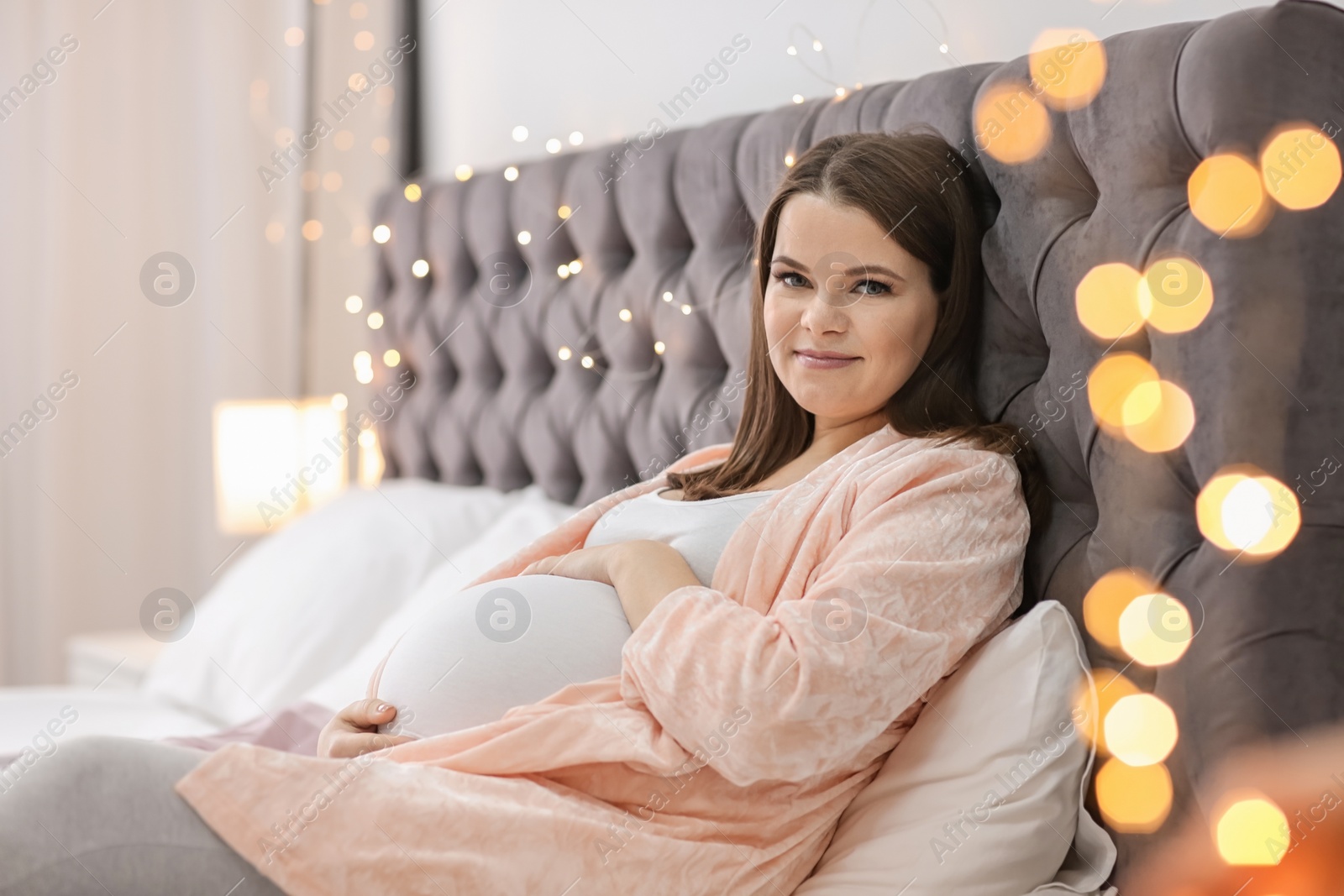 Photo of Beautiful pregnant woman lying on bed at home