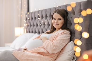 Beautiful pregnant woman lying on bed at home