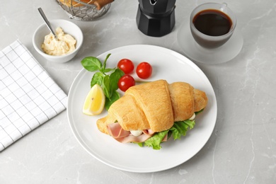 Photo of Tasty croissant sandwich with sausage on light background