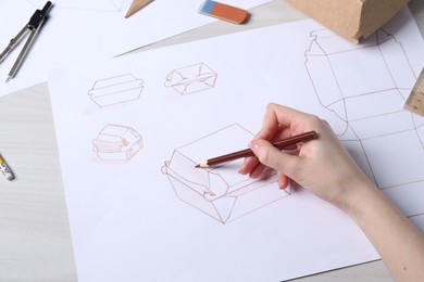 Photo of Woman creating packaging design at light wooden table, above view