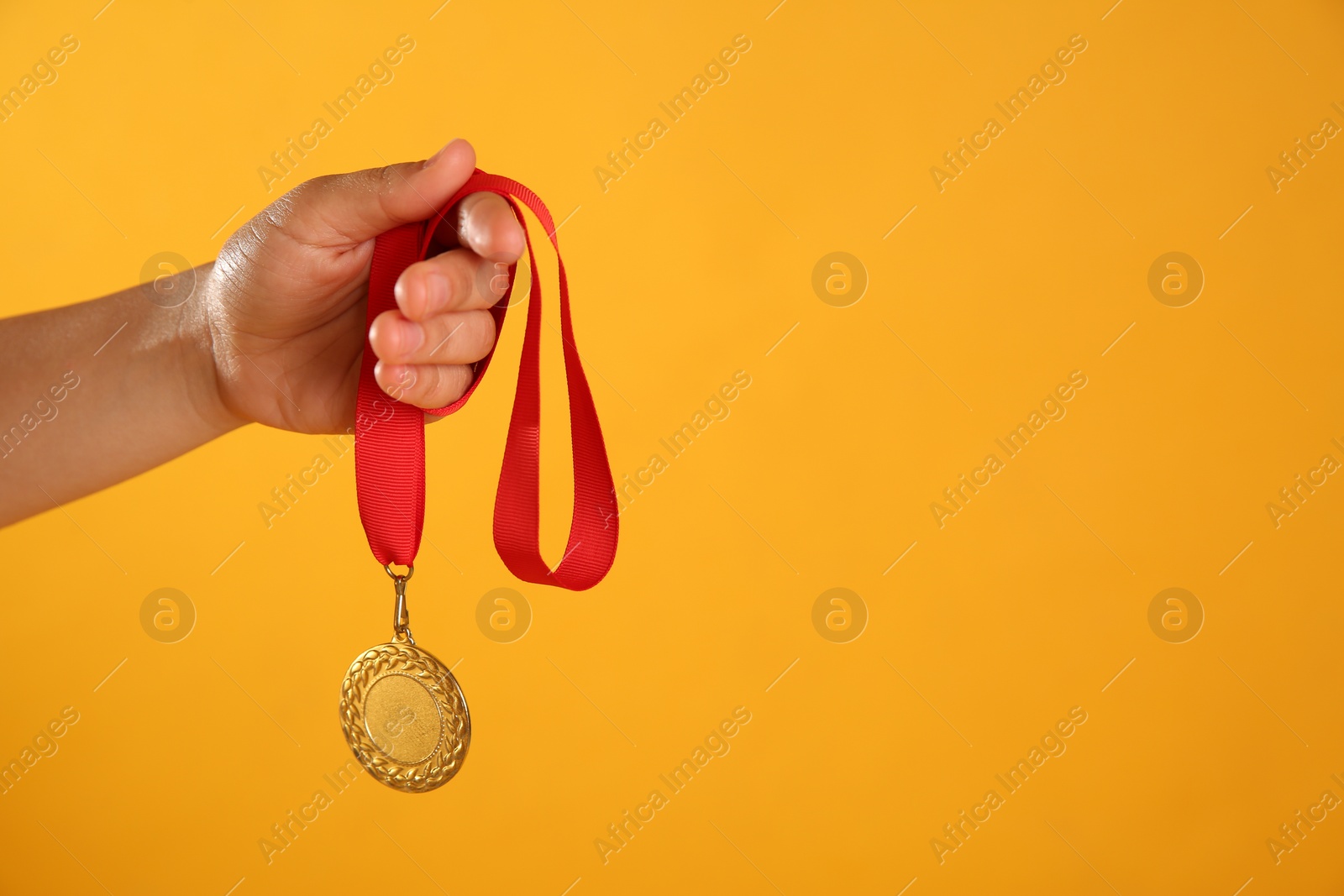 Photo of Woman holding gold medal on yellow background, closeup. Space for text