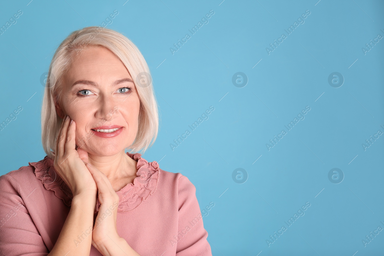 Photo of Portrait of charming mature woman with healthy beautiful face skin and natural makeup on blue background, space for text