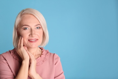 Portrait of charming mature woman with healthy beautiful face skin and natural makeup on blue background, space for text