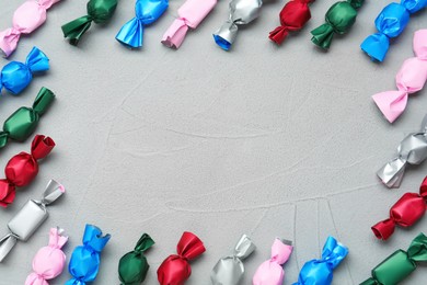 Frame of candies in colorful wrappers on grey table, flat lay. Space for text