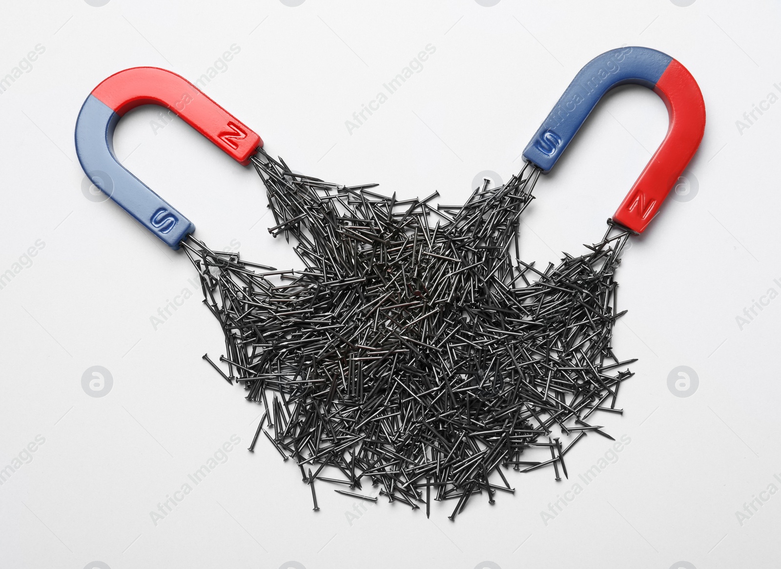 Photo of Horseshoe magnets attracting nails on white background, top view