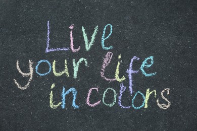 Photo of Phrase Live Your Life In Colors written on asphalt, top view