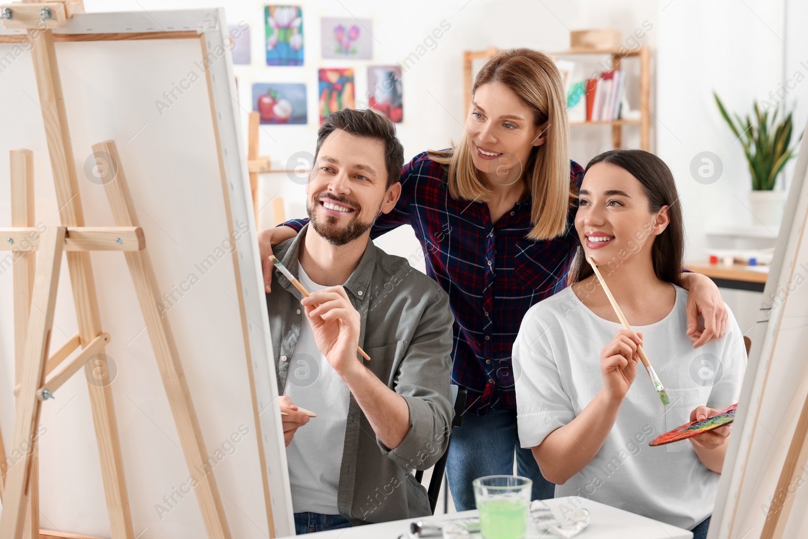 Photo of Artist teaching her students to paint in studio. Creative hobby