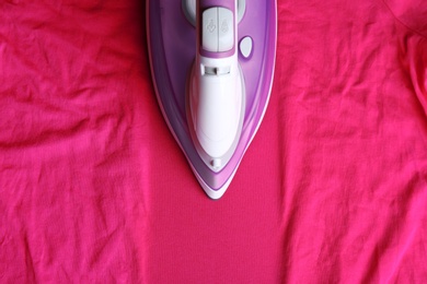 Modern electric iron on wrinkled cloth, top view