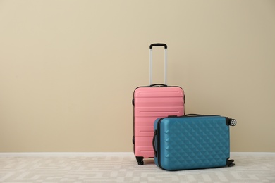 Photo of Modern suitcases on floor near light wall. Space for text