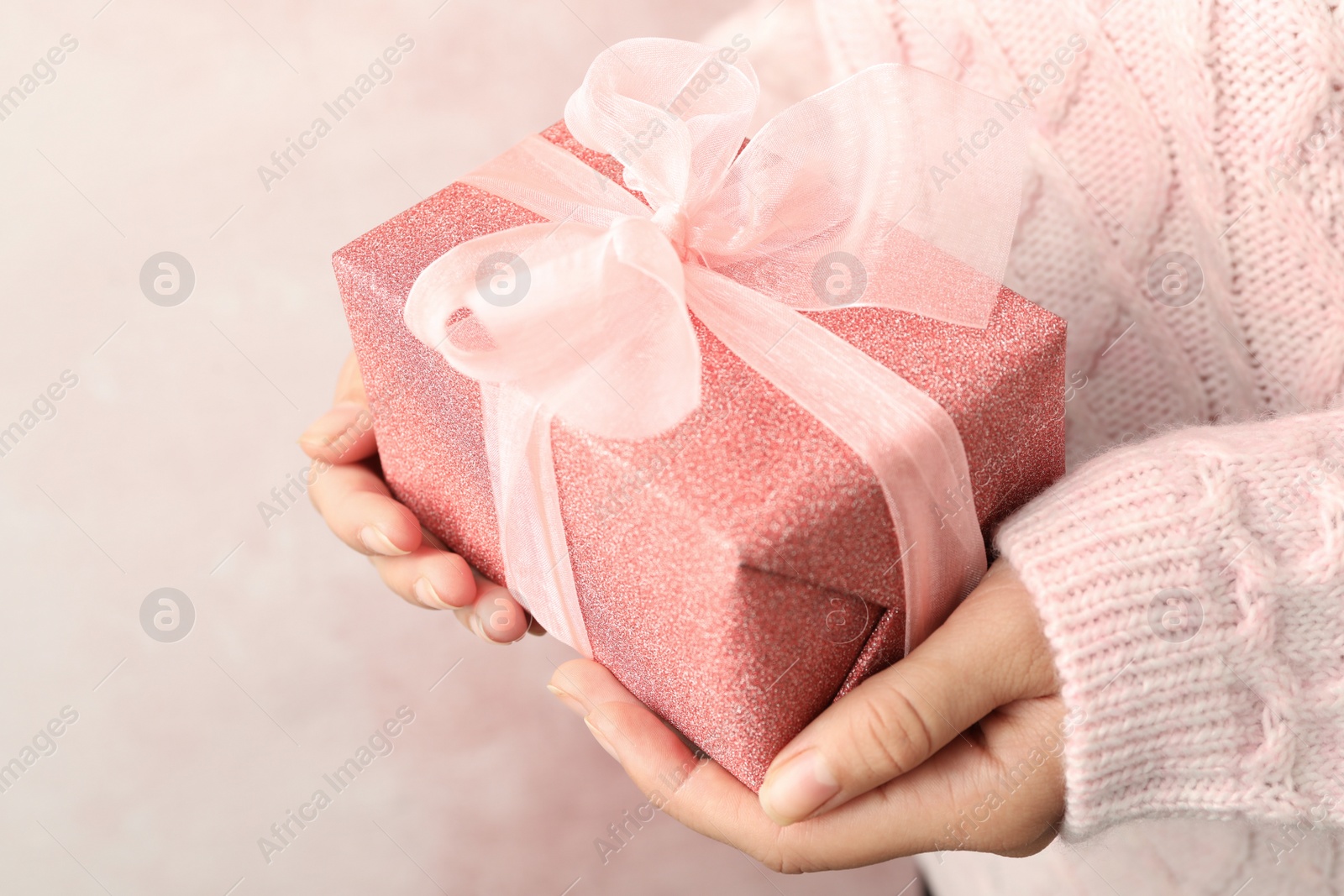 Photo of Woman holding beautiful Christmas gift on light background, closeup