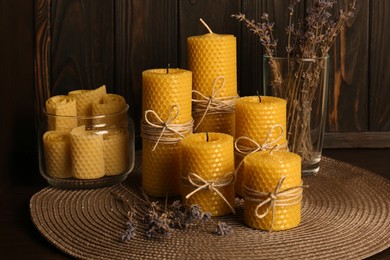 Photo of Beautiful beeswax candles and dried lavender flowers on table
