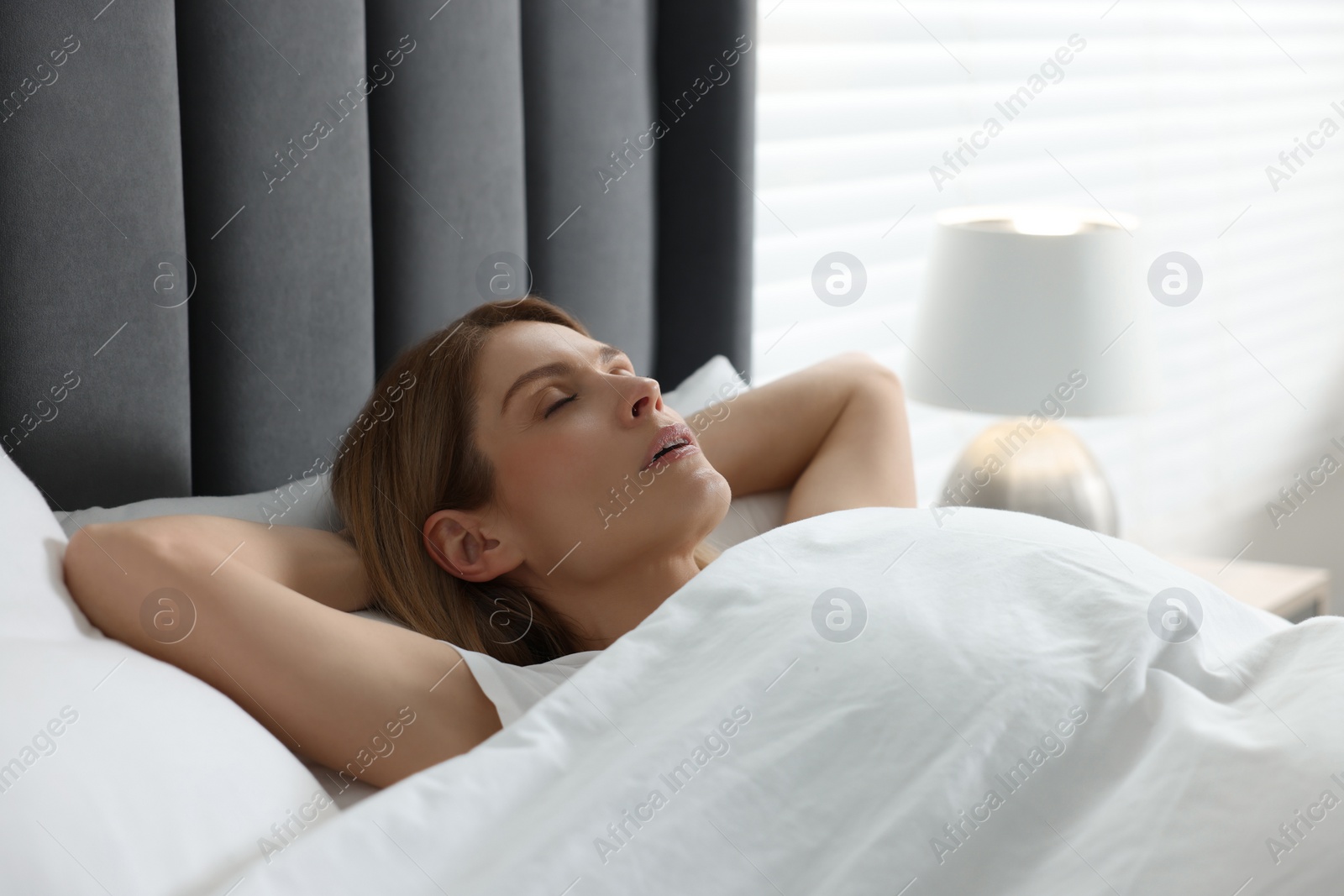 Photo of Woman snoring while sleeping in bed at home