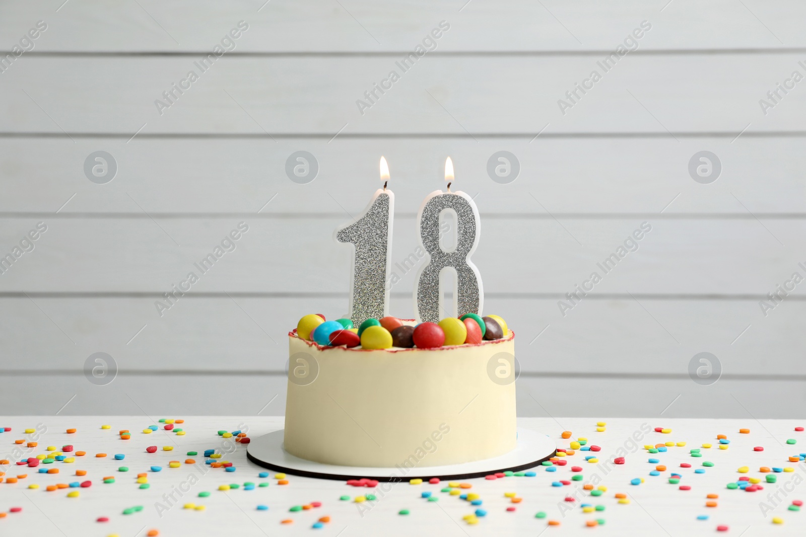 Photo of Coming of age party - 18th birthday. Delicious cake with number shaped candles on white table