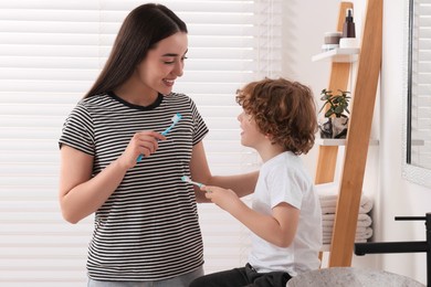 Mother and her son brushing teeth together in bathroom