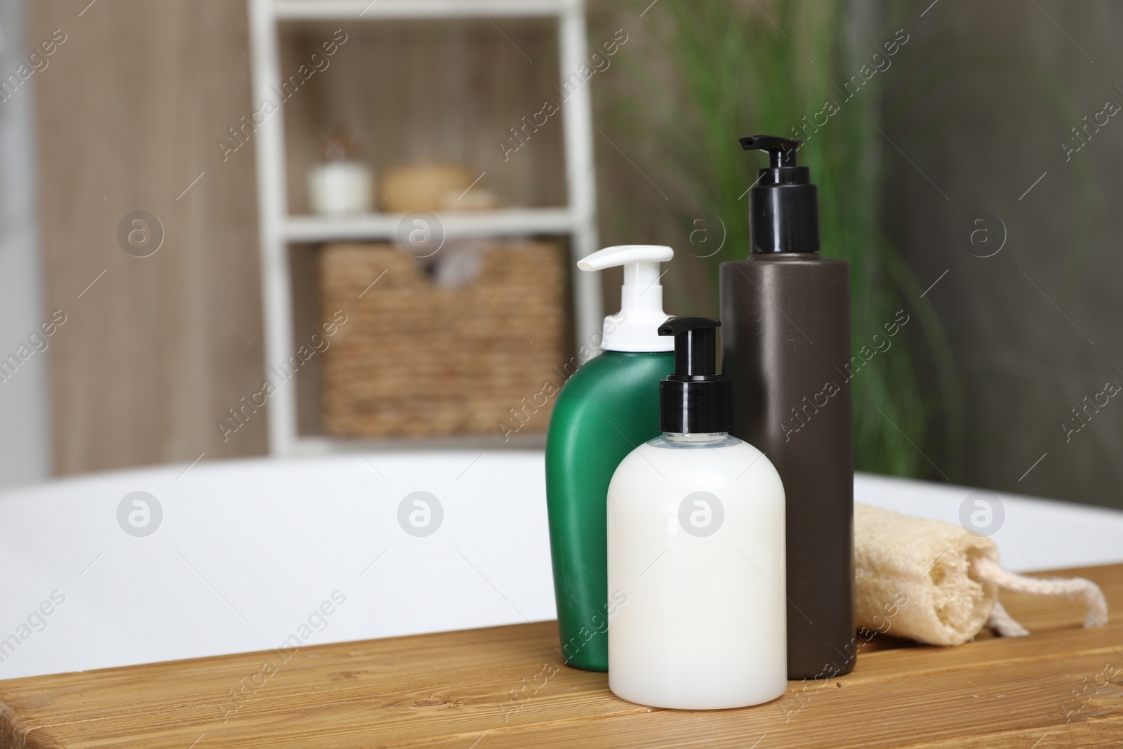 Photo of Bottles of shower gels and loofah on wooden table indoors, space for text