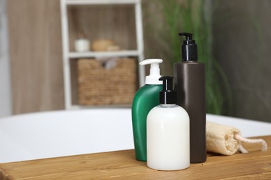 Bottles of shower gels and loofah on wooden table indoors, space for text