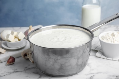 Photo of Delicious creamy sauce in pan on marble table