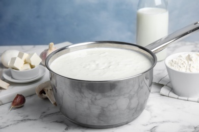 Delicious creamy sauce in pan on marble table