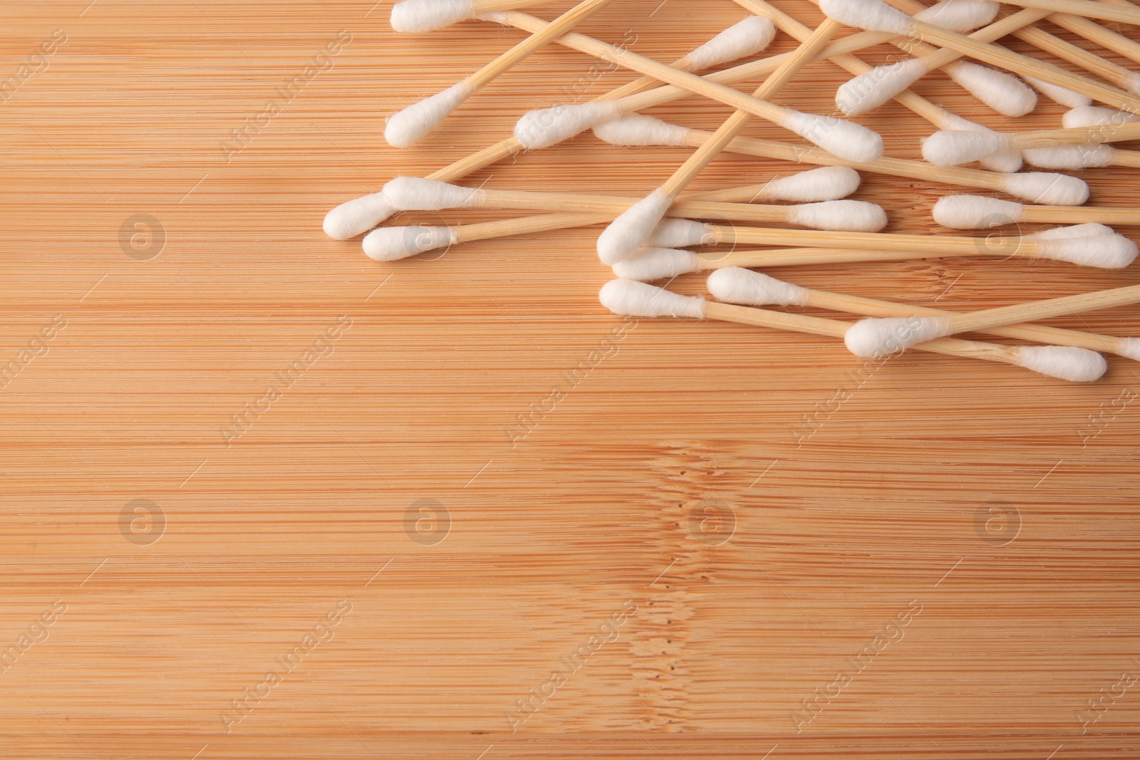 Photo of Heap of clean cotton buds on wooden table, flat lay. Space for text